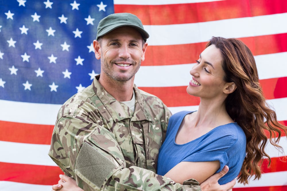 Handsome soldier reunited with partner against an american flag